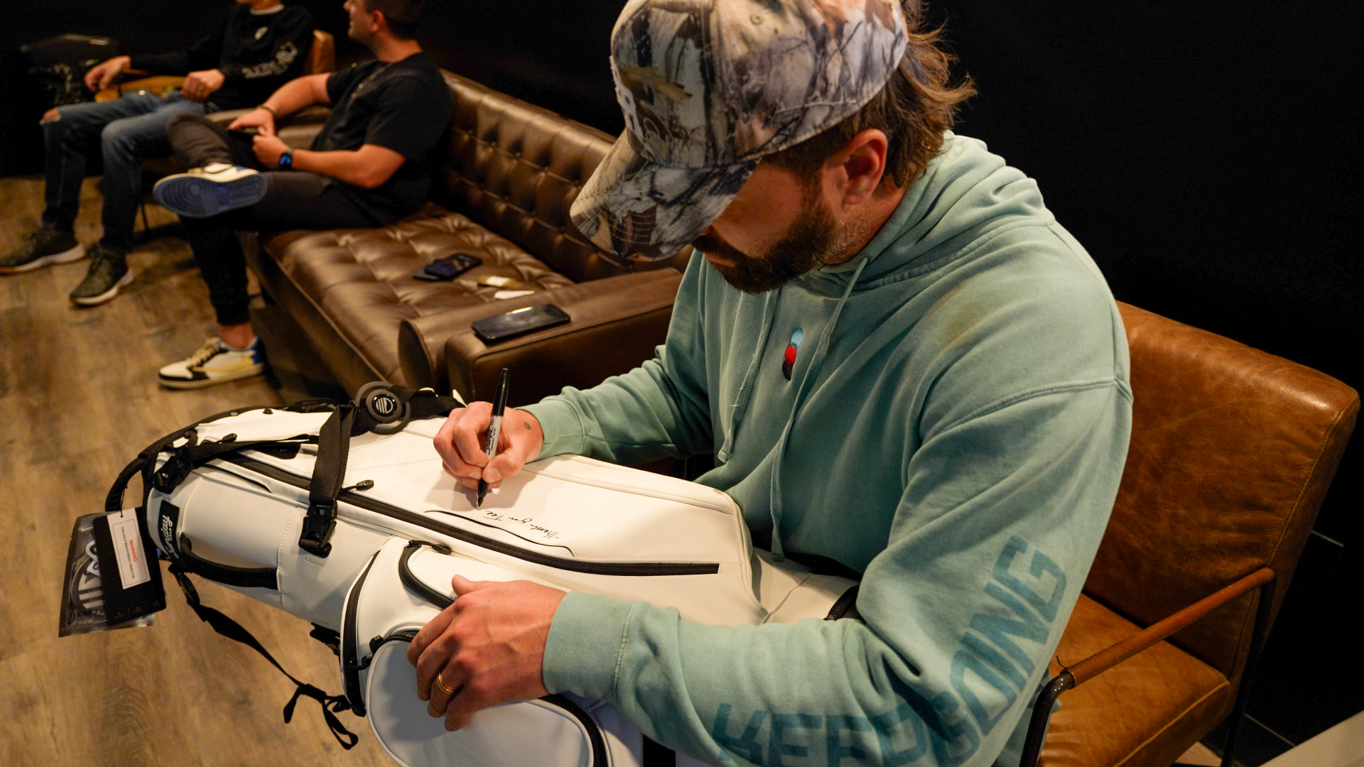 Founder signing a golf bag at a Coinlete event