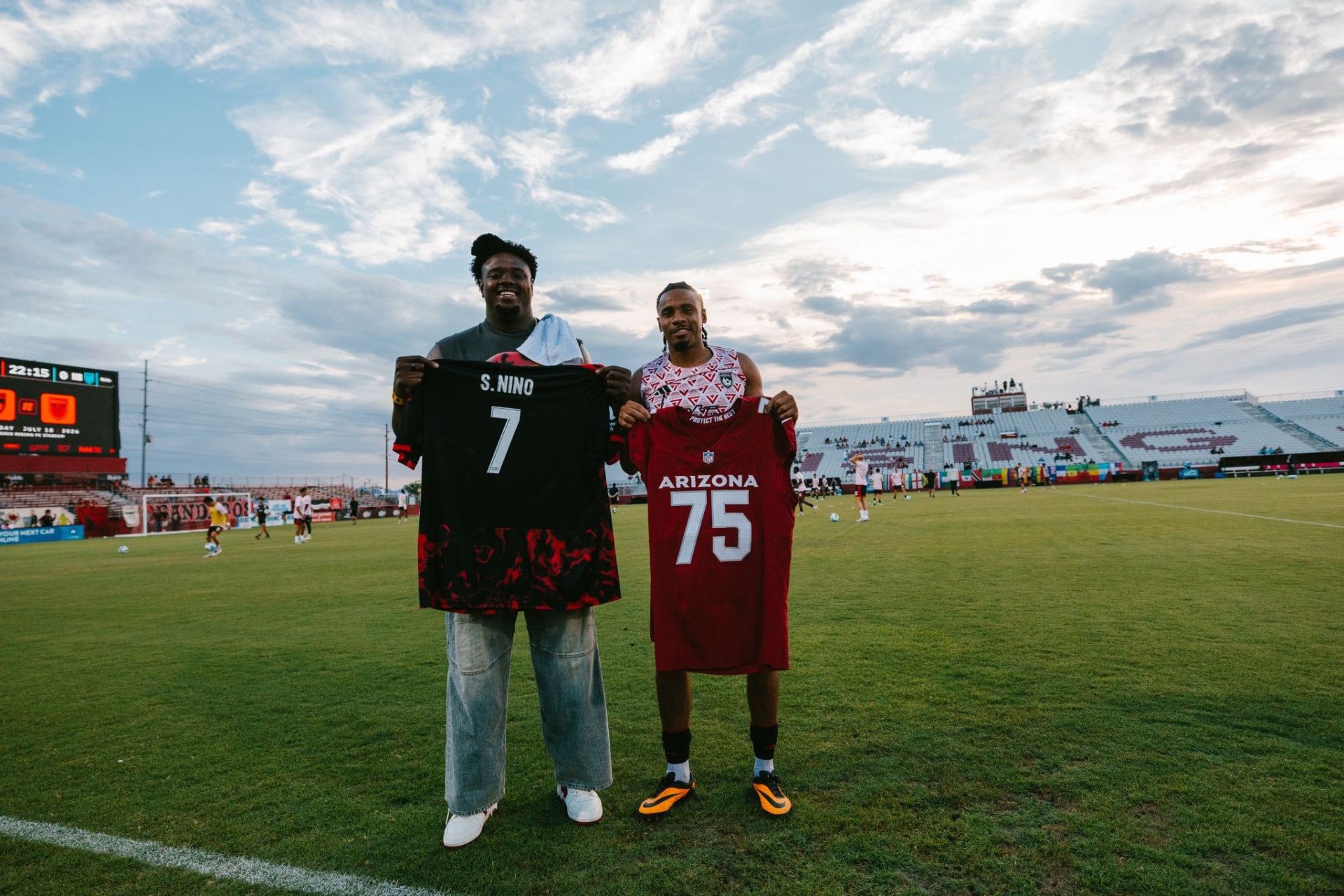Athletes holding jerseys on the field at a client event