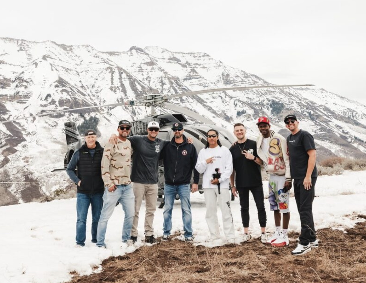 Coinlete partners and athletes gathered in front of a helicopter in the mountains